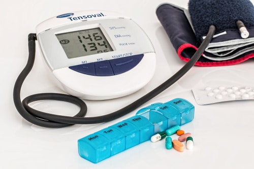 Low testosterone effects (weekly pill container with pills in front, digital blood pressure machine and cuff, pills sealed in aluminum packaging)
