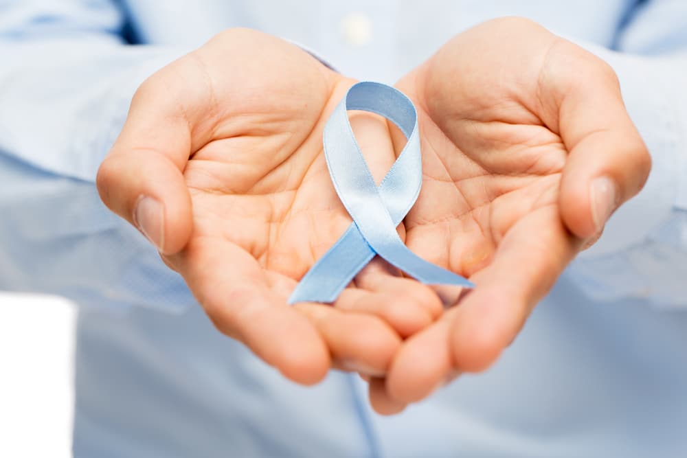 The cause of prostate cancer is not well understood. hands with blue prostate cancer awareness ribbon