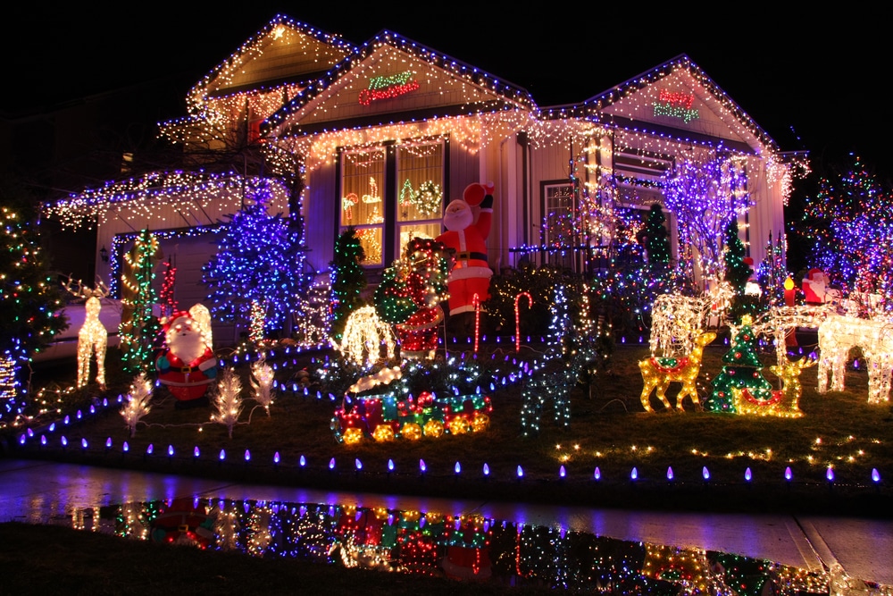 Christmas lights in many colors decorate a large house, and a reflection of the display can be seen in water in the foreground. Viewing holiday lights is one of the many holiday events in Prosper. 