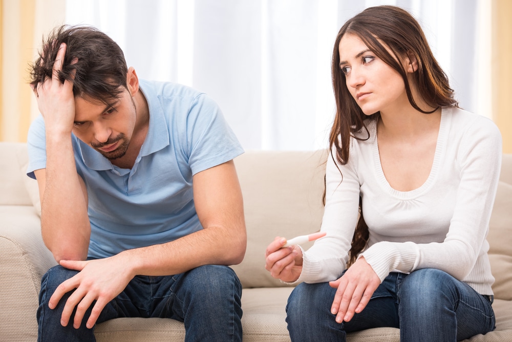 A disappointed woman holding a pregnancy test sitting on a couch next to a frustrated man. hCG may be used in lieu of testosterone injections to preserve fertility in men who suffer from low testosterone. Learn more.