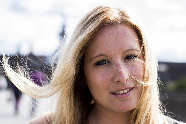 A middle-aged blonde woman smiles sadly at the camera. She looks concerned, and she may be suffering from low estrogen, a common problem for women.