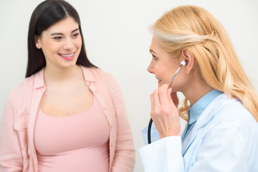A dark-haired woman laughs with her female doctor. She may be having a consultation regarding the effects of low estrogen on women.