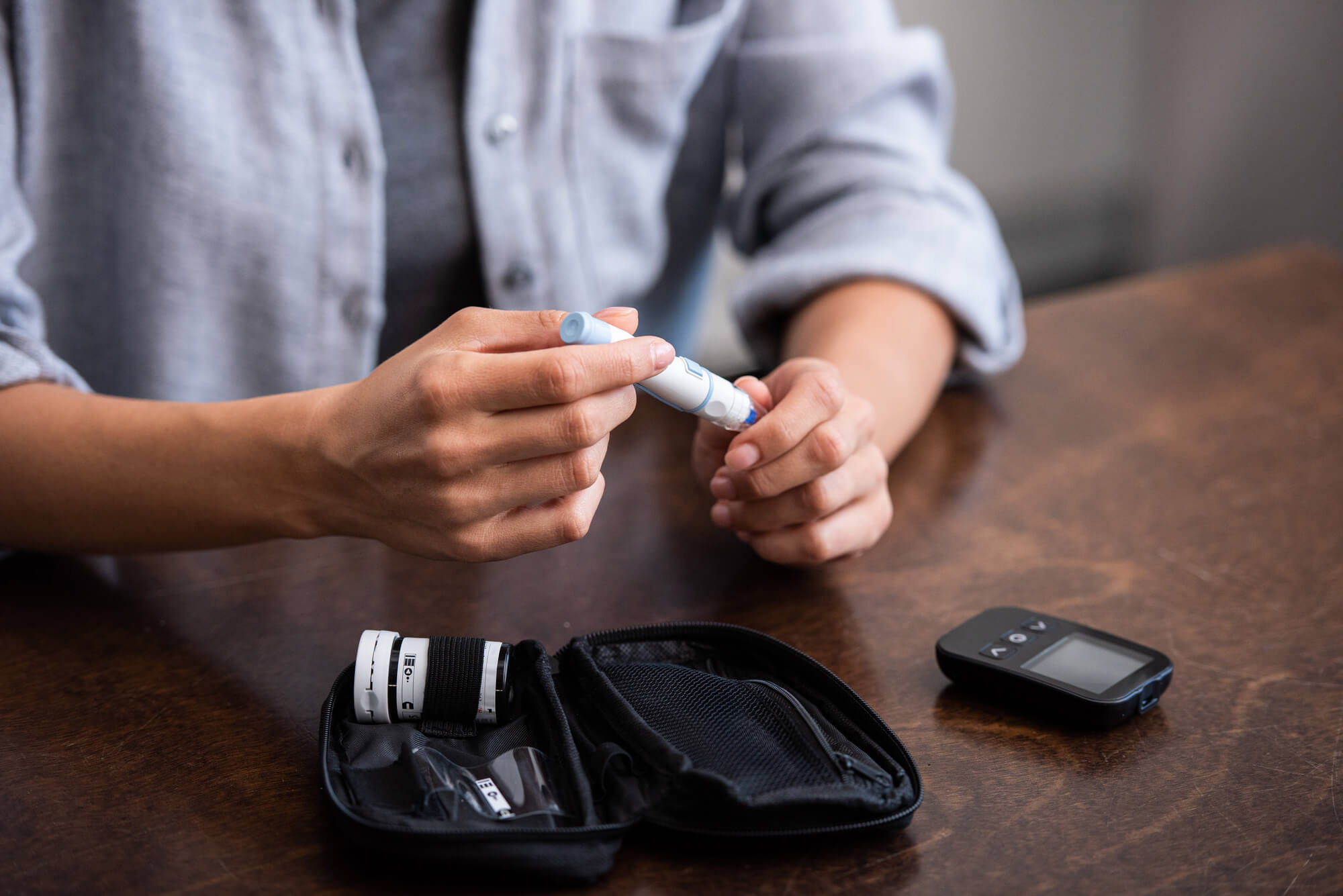 A man checks his blood sugar while sitting at a brown table. TRT and diabetes remission are connected according to recent research.