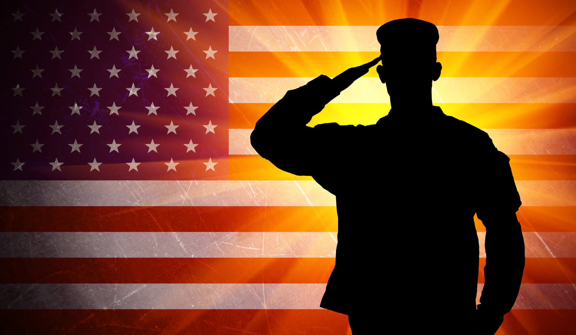 A silhouetted soldier salutes against an American Flag background. Low testosterone can be a concern for veterans due to stressful conditions.