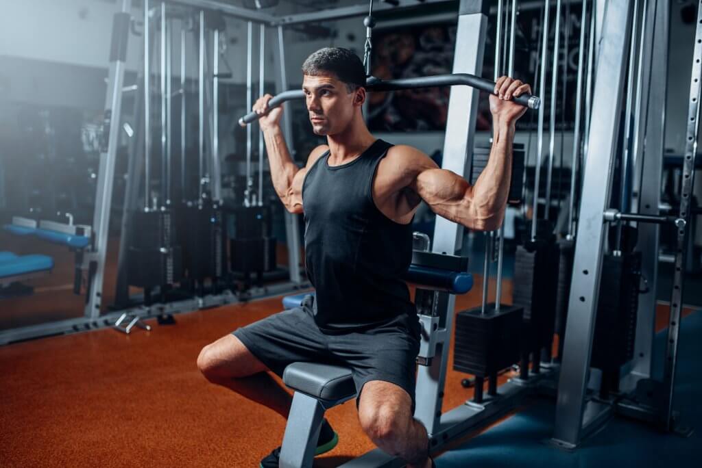 Man on a weight bench does lat pulls to increase muscle mass. Testosterone is critical to good health..