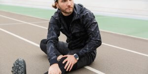 A man in a black training suit stretches while sitting on a running track in cool weather. Do testosterone levels fluctuate naturally or seasonally?
