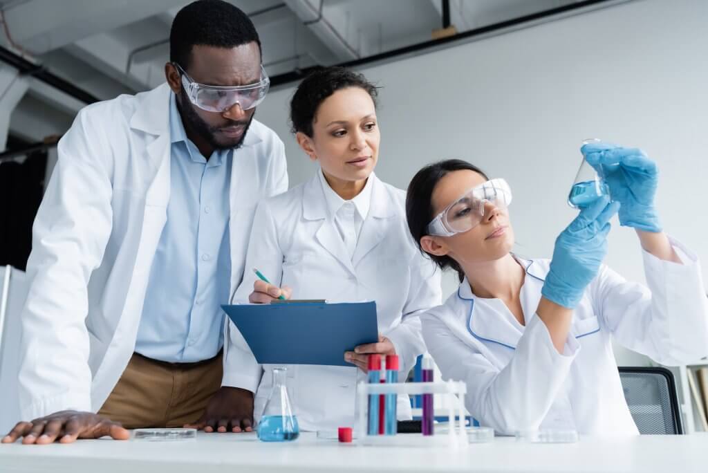 Three medical lab techs examine a test tube as part of free T testing that will provide guidance for treatment and other TRT benefits.