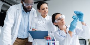 Three medical lab techs examine a test tube as part of free T testing that will provide guidance for treatment and other TRT benefits.