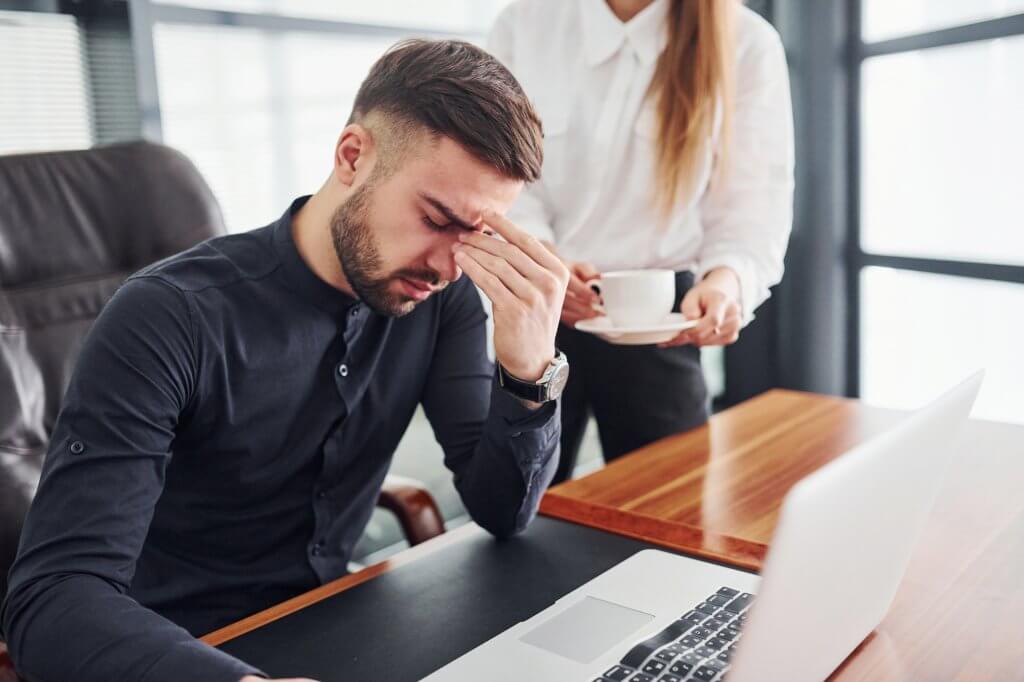 A man sitting at a desk, visibly feeling a lot of stress.