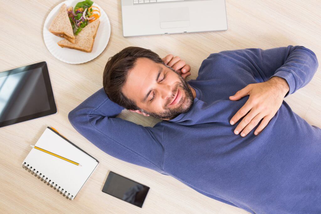 A man is lying in the floor, peacefully napping. Napping may increase brain volume.