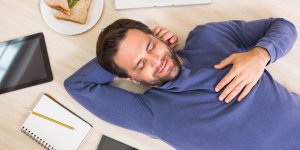 A man is lying in the floor, peacefully napping. Napping may increase brain volume.