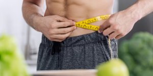 A man measures his waist. He's possibly using semaglutide for weight loss.